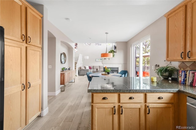 kitchen with light brown cabinets, a peninsula, open floor plan, tile countertops, and light wood-type flooring