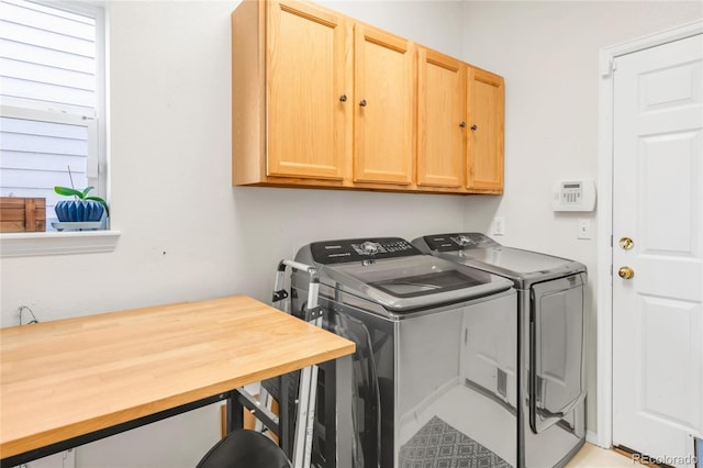 clothes washing area with separate washer and dryer and cabinet space