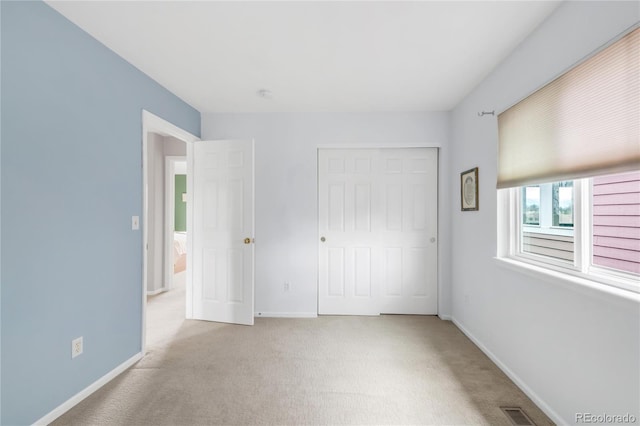 unfurnished bedroom with carpet floors, baseboards, a closet, and visible vents