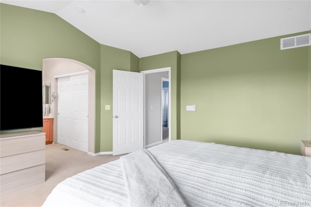 bedroom featuring visible vents, baseboards, light colored carpet, arched walkways, and vaulted ceiling