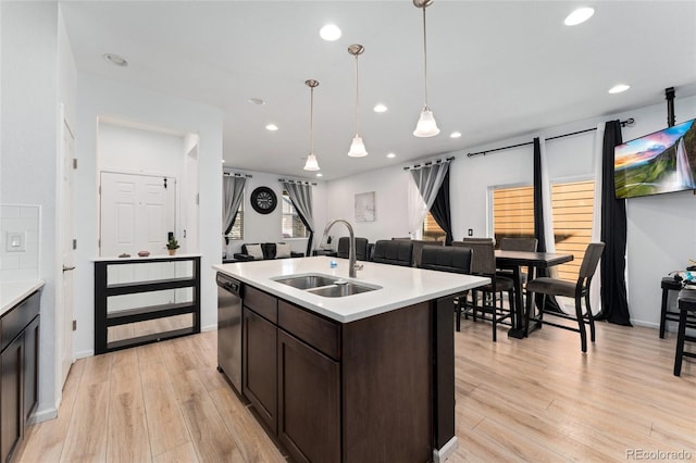 kitchen with dark brown cabinets, stainless steel dishwasher, light hardwood / wood-style flooring, sink, and decorative light fixtures