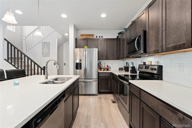 kitchen with appliances with stainless steel finishes, decorative backsplash, sink, dark brown cabinets, and pendant lighting