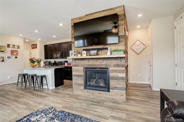 4316 S Netherland St, Aurora, CO 80015 - kitchen with stainless steel microwave, a kitchen breakfast bar, light wood-style floors, baseboards, and recessed lighting