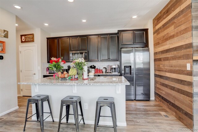 4316 S Netherland St, Aurora, CO 80015 - kitchen with appliances with stainless steel finishes, a breakfast bar area, a center island with sink, light stone countertops, and recessed lighting