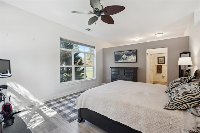 bedroom with wood finished floors, baseboards, a ceiling fan, and ensuite bathroom