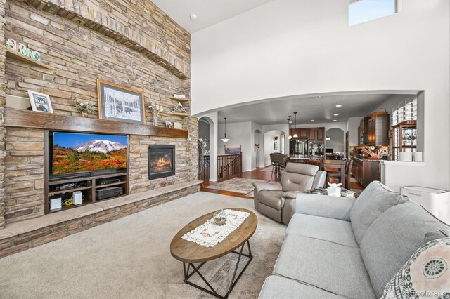 2373 S Joyce St, Denver, CO 80228 - carpeted living area featuring arched walkways, a towering ceiling, and a stone fireplace