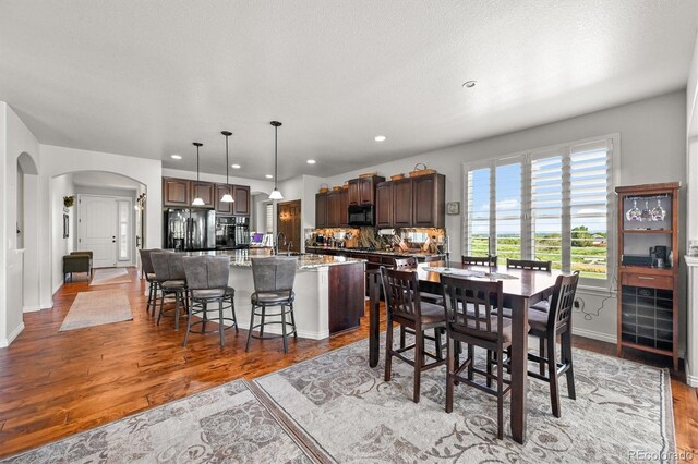2373 S Joyce St, Denver, CO 80228 - dining space featuring arched walkways, wood finished floors, baseboards, and recessed lighting