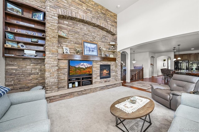 2373 S Joyce St, Denver, CO 80228 - living area with arched walkways, a stone fireplace, carpet, and a high ceiling