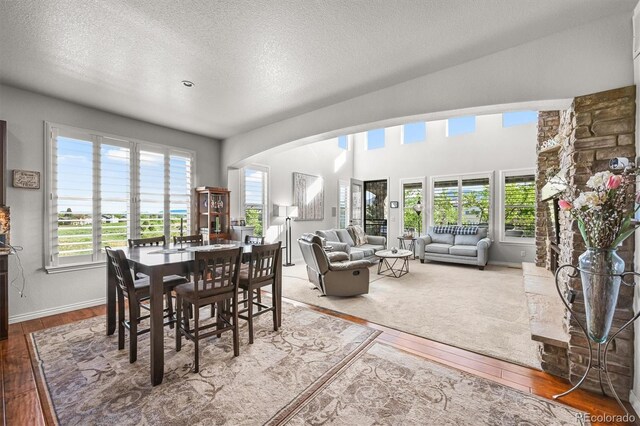 2373 S Joyce St, Denver, CO 80228 - dining area featuring hardwood / wood-style flooring, arched walkways, a textured ceiling, and baseboards