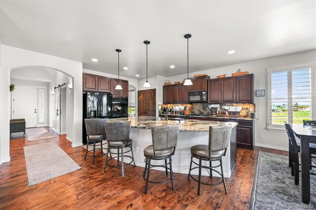 2373 S Joyce St, Denver, CO 80228 - kitchen featuring black appliances, arched walkways, dark brown cabinetry, dark wood-style flooring, and recessed lighting