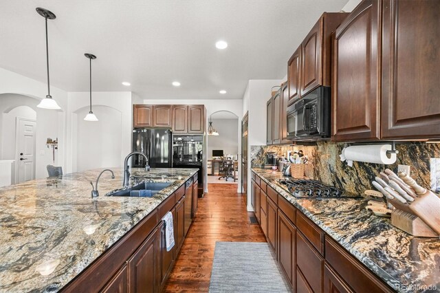 2373 S Joyce St, Denver, CO 80228 - kitchen featuring black appliances, arched walkways, a sink, dark wood finished floors, and stone counters