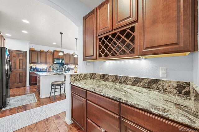 2373 S Joyce St, Denver, CO 80228 - kitchen with black appliances, light wood-type flooring, arched walkways, light stone counters, and recessed lighting