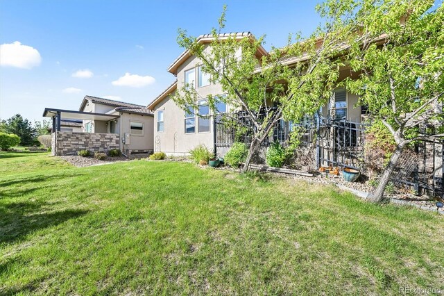 2373 S Joyce St, Denver, CO 80228 - rear view of property with stucco siding, a lawn, and a tiled roof