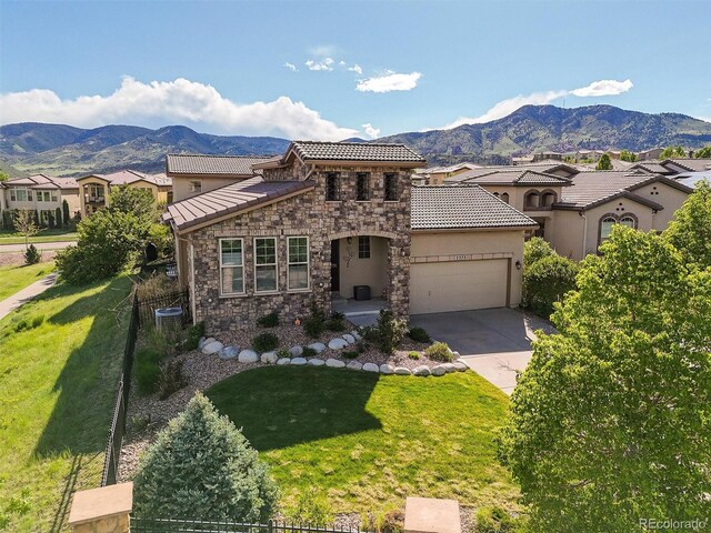 2373 S Joyce St, Denver, CO 80228 - mediterranean / spanish home featuring a mountain view, stone siding, an attached garage, stucco siding, and concrete driveway