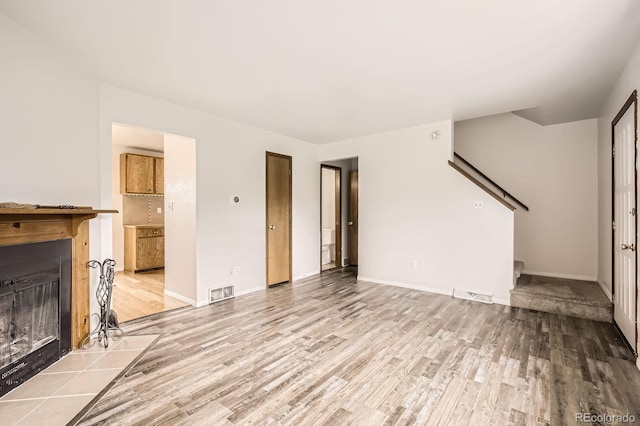 3021 11th Ave Unit 15, Evans, CO 80620 - unfurnished living room featuring wood finished floors, a fireplace with flush hearth, stairs, and baseboards
