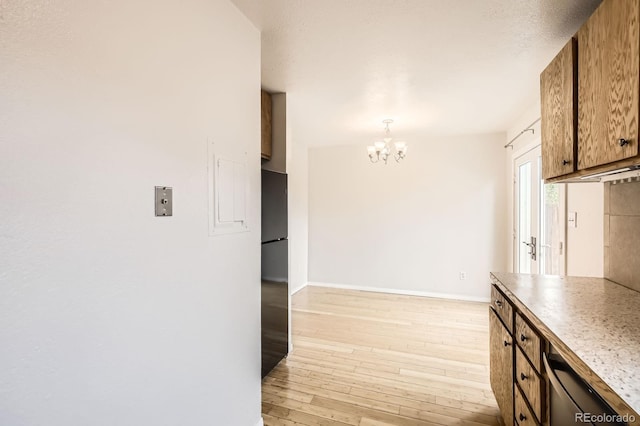 3021 11th Ave Unit 15, Evans, CO 80620 - kitchen with a chandelier, light wood-style floors, baseboards, freestanding refrigerator, and brown cabinetry