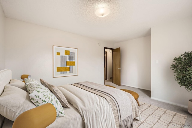 3021 11th Ave Unit 15, Evans, CO 80620 - bedroom with light colored carpet, a textured ceiling, and baseboards