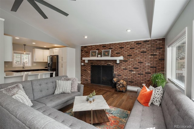 5382 S Pine Rd, Evergreen, CO 80439 - living area with wood finished floors, brick wall, ceiling fan, a fireplace, and vaulted ceiling