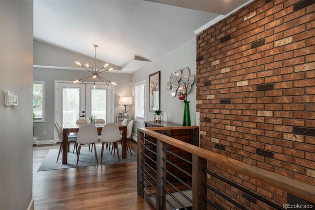 5382 S Pine Rd, Evergreen, CO 80439 - dining space with lofted ceiling, healthy amount of natural light, wood finished floors, a chandelier, and brick wall