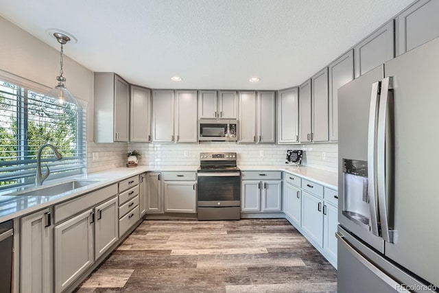 kitchen featuring backsplash, gray cabinetry, stainless steel appliances, and a sink