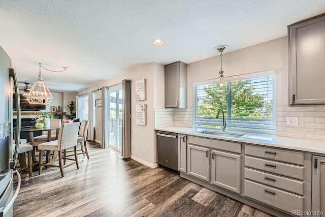 kitchen with gray cabinetry, dark wood finished floors, light countertops, stainless steel appliances, and a sink