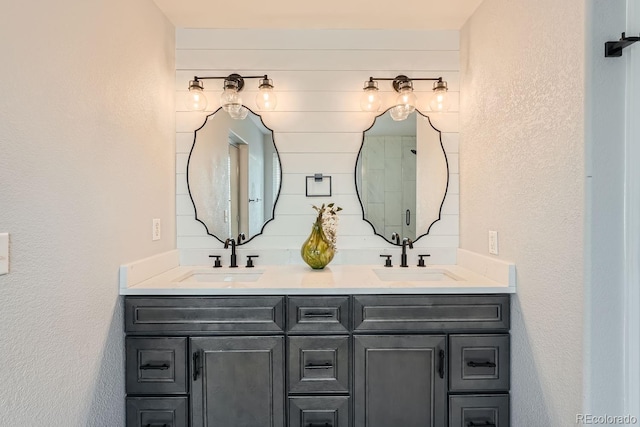 bathroom with double vanity, a textured wall, and a sink