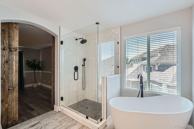 full bath with a soaking tub, a shower stall, baseboards, and wood finished floors