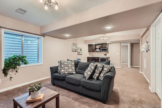 living room with light carpet, visible vents, a chandelier, and baseboards