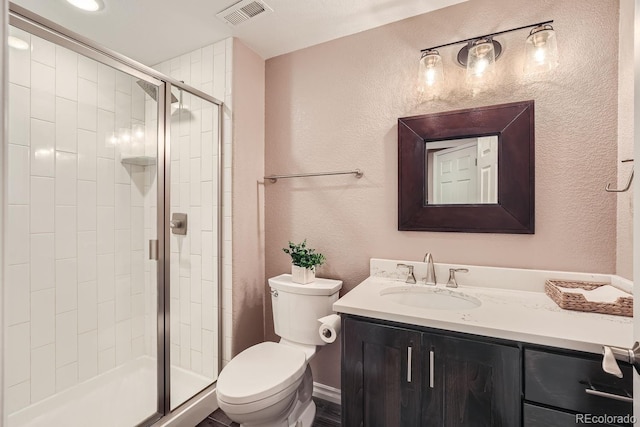 bathroom featuring vanity, visible vents, a shower stall, toilet, and a textured wall