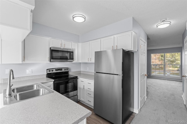 kitchen with white cabinetry, sink, light colored carpet, a textured ceiling, and appliances with stainless steel finishes