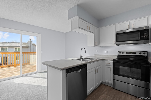 kitchen featuring white cabinets, sink, a textured ceiling, appliances with stainless steel finishes, and kitchen peninsula