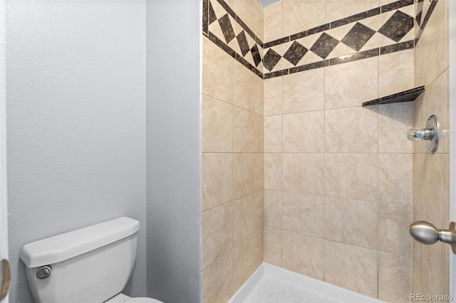 bathroom with toilet and a tile shower