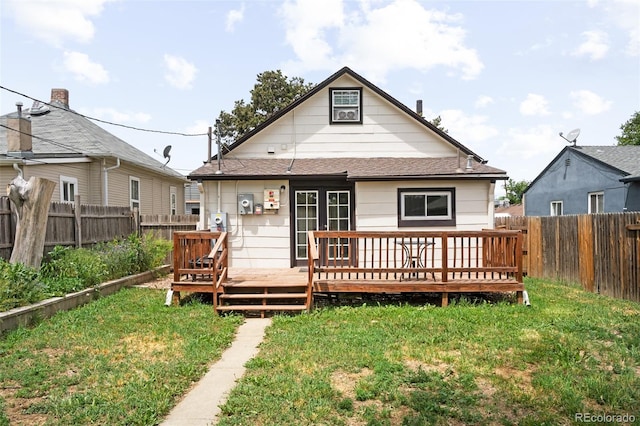 back of property with a lawn and a deck