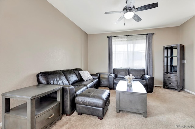 living area featuring light carpet, a ceiling fan, and baseboards