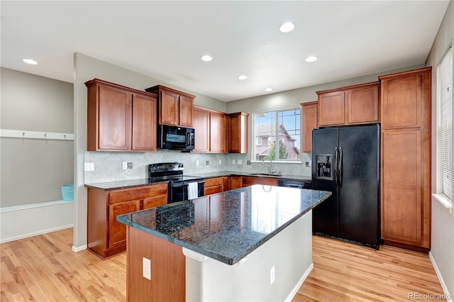 kitchen with black appliances, light wood-style flooring, brown cabinetry, and a sink