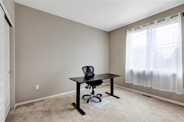 office space featuring light carpet, visible vents, and baseboards