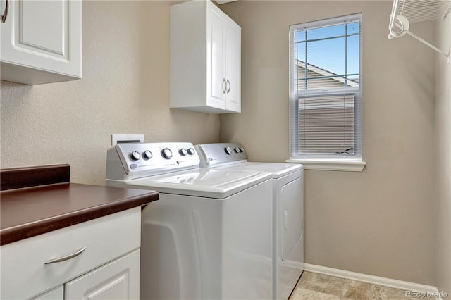 washroom with cabinet space, baseboards, and washer and clothes dryer