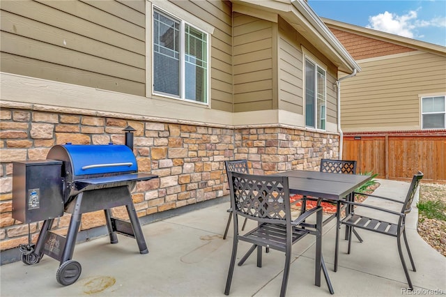 view of patio featuring outdoor dining space, fence, and grilling area