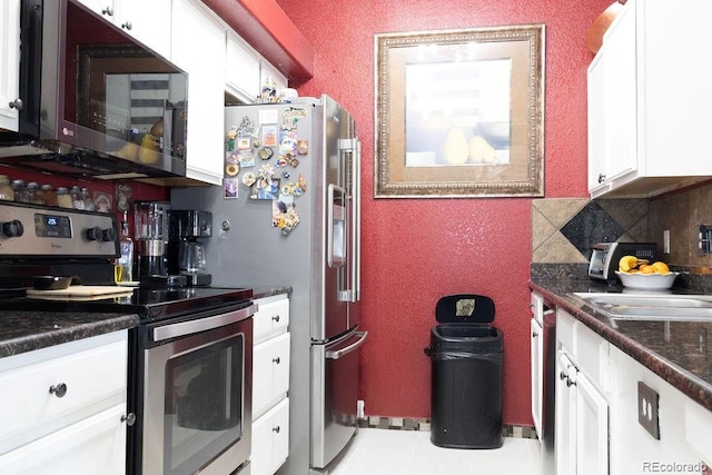 kitchen with tasteful backsplash, white cabinets, stainless steel appliances, sink, and tile patterned floors