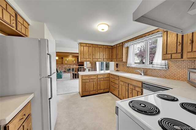 kitchen featuring white appliances, wall chimney range hood, a sink, brown cabinets, and light countertops
