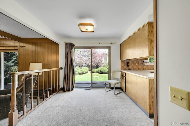 sitting room featuring light carpet, plenty of natural light, and wooden walls