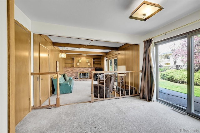carpeted living room featuring wooden walls and beamed ceiling