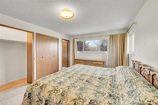 bedroom featuring multiple closets, light carpet, and a textured ceiling