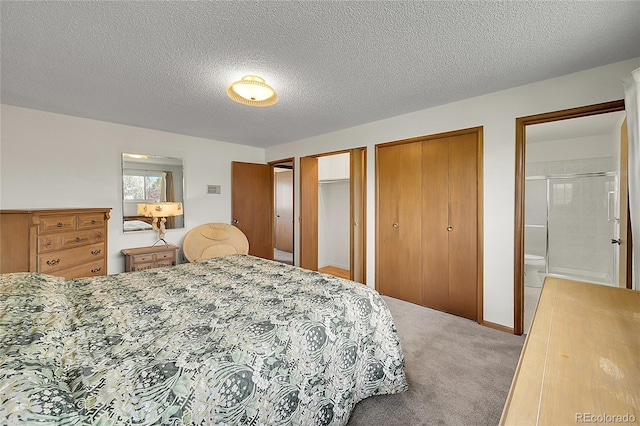 carpeted bedroom with multiple closets, a textured ceiling, and connected bathroom