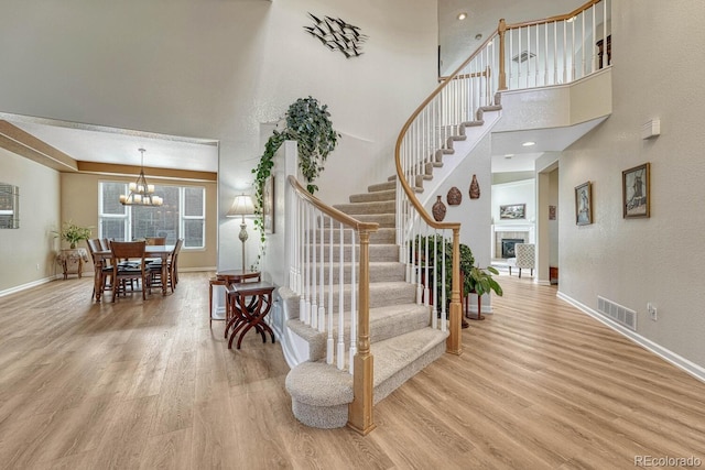 598 Crossing Cir, Castle Pines, CO 80108 - stairway featuring wood finished floors, baseboards, a towering ceiling, and a chandelier