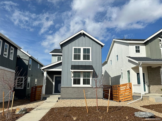 view of front of home with board and batten siding, brick siding, and a porch