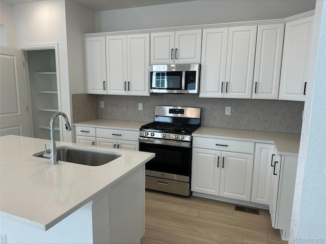 kitchen with a sink, visible vents, white cabinets, appliances with stainless steel finishes, and light wood-type flooring