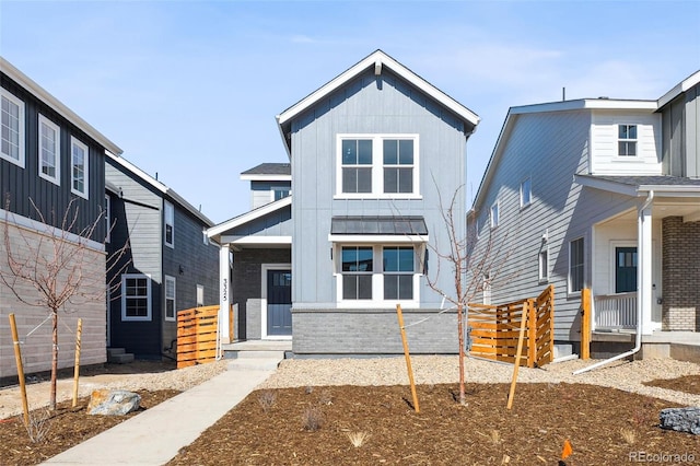 view of front of house with a standing seam roof, covered porch, brick siding, and board and batten siding