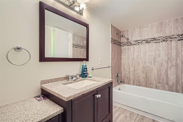 bathroom featuring tiled shower / bath, vanity, and a textured ceiling