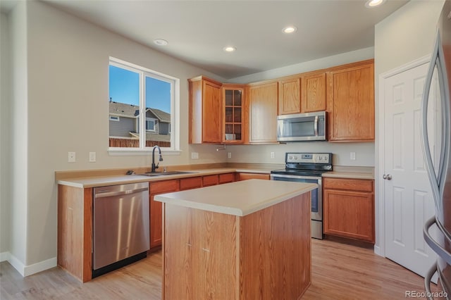 kitchen featuring stainless steel appliances, a kitchen island, sink, and light hardwood / wood-style flooring